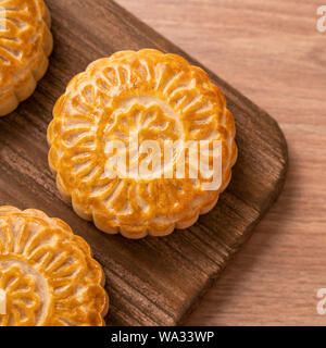 Runde frisch gebackene Mond kuchen Gebäck - Chinesische moonckae für Mid-Autumn Moon Festival auf hölzernen Hintergrund und Serviertablett, Ansicht von oben, flach. Stockfoto