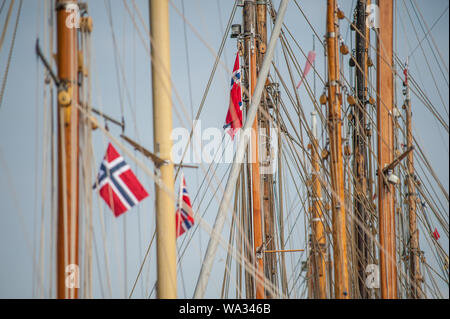 Norwegische Flaggen hängen von den Masten der alten hölzernen Segelbooten. Stockfoto