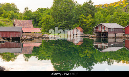 Alte, verwitterte Boot Häuser mit schönen Wasser Reflexionen in einer kleinen Bucht. Stockfoto