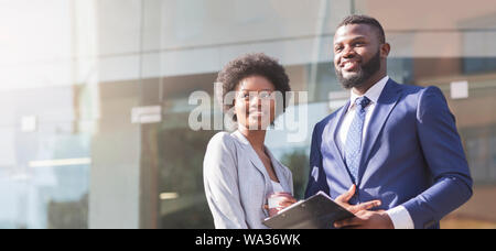 Paar Geschäftspartner gegen moderne Gebäude aus Glas Hintergrund stehend Stockfoto