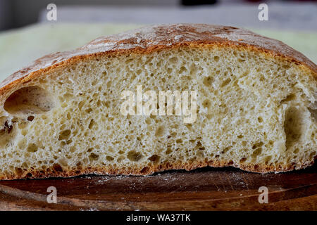 Nahaufnahme von frisch gebackenem Brot im rustikalen Stil/Frischer runde Brot mit einer schönen Kruste liegt auf einem Holzbrett/hausgemachtes Brot Stockfoto