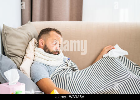 Hohe Temperatur Konzept. Mann fühlt sich schwer krank. Wie Fieber senken. Kalte Symptome und Ursachen. Kranken Mann mit Grippe. Mann Thermometer. Messen tem Stockfoto