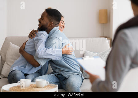 Gerne Afrikanische amerikanische Paar umarmt nach Versöhnung an der Psychologe Büro Stockfoto