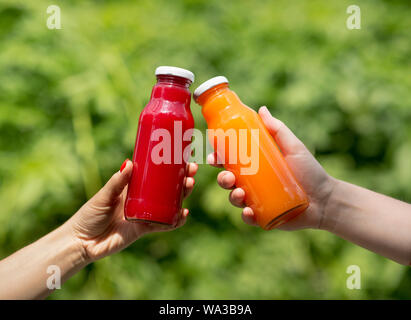 Zwei Hände, die detox Cocktails auf grüner Baum Hintergrund Stockfoto