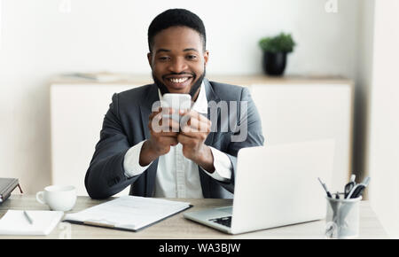 Happy Geschäftsmann auf dem Smartphone im Internet surfen, Arbeiten im Büro Stockfoto
