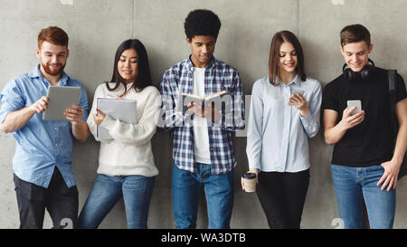 Diverse Studenten mit Bücher stehen in der Nähe der graue Wand Stockfoto