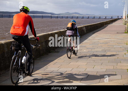 Tayside Dundee, Schottland, Großbritannien, 17. August 2019: BRITISCHE Wetter. Sonnig und kühlen Morgen in Dundee mit verstreuten Duschen später am Tag entwickelt, maximale Temperatur 18°C. Ein paar Radfahrer Radfahren entlang der Stadt Uferpromenade mit Blick auf den berühmten 1800 'Stay Eisenbahnbrücke in der Ferne. Credit: Dundee Photographics/Alamy leben Nachrichten Stockfoto