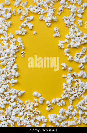 Grenze von Popcorn über Gelb Hintergrund mit Kopie Raum verstreut, Ansicht von oben. Minimalistisches Design für Film Poster, Unterhaltung Konzept. Nahaufnahme der Stockfoto