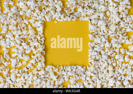 Grenze von Popcorn über Gelb Hintergrund mit Kopie Raum verstreut, Ansicht von oben. Minimalistisches Design für Film Poster, Unterhaltung Konzept. Nahaufnahme der