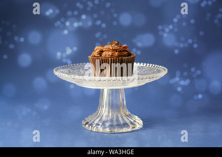 Geburtstag Cupcake mit Schokoladencreme auf eine Glasschale, blau Hintergrund mit bokeh Lichter, Kopieren, ausgewählte konzentrieren, enge Tiefenschärfe Stockfoto