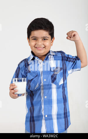Junge hält ein Glas Milch und Angeberei Muskeln Stockfoto