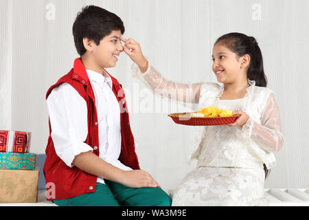 Mädchen, die Anwendung von Tika auf der Stirn Bruder Raksha Bandhan Festival Stockfoto