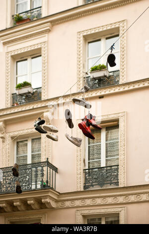 Zeigt hängen durch ihre Schnürsenkel aus Zeile zwischen den Wohnhäusern. Bezirk Marais, Paris, Frankreich Stockfoto