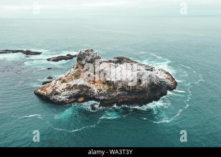 Luftdrohne Aufnahme einer kleinen Felseninsel in der Blaues, wunderschönes Meer Stockfoto