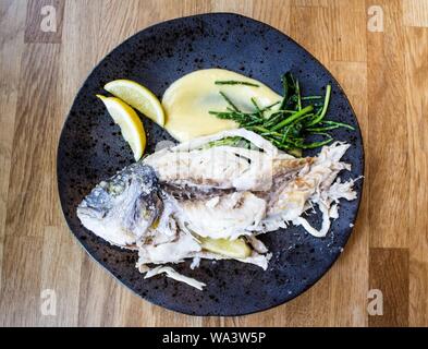 Overhead Schuss von einem rohen Fisch mit Zitronen auf einem Runde Platte Stockfoto