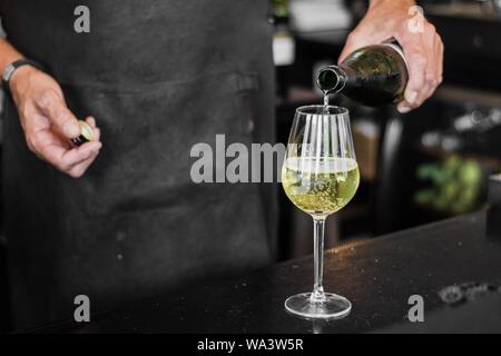 Nahaufnahme des Barkeepers, der Wein in ein Glas eingießt Mit unscharfem Hintergrund Stockfoto