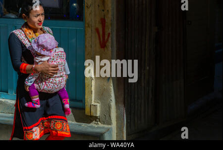 Kathmandu, Nepal-November 02,2017: Junge nepalesische Frauen trägt ihr Baby in einem babytragetuch Stockfoto