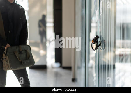 Die bürotür mit Metall Kette und einem Vorhängeschloss gesichert. Und ein Mann vorbei, mit einem großen Schultertasche. Stockfoto