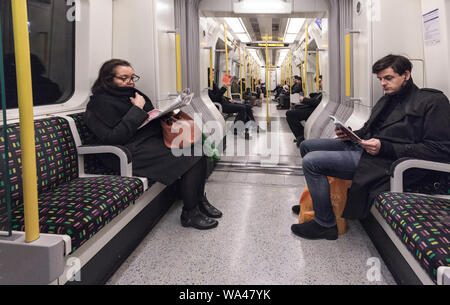 Passagiere lesen und Ignorieren einander sitzen in Stille auf einer Londoner U-Bahn Linie Zug Richtung Westen von der Earls Court Stockfoto