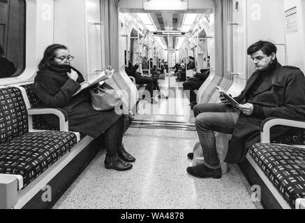 Passagiere lesen und Ignorieren einander sitzen in Stille auf einer Londoner U-Bahn Linie Zug Richtung Westen von der Earls Court Stockfoto