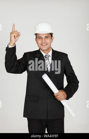 Männlicher Architekt, der einen Bauplan hält und nach oben zeigt Stockfoto