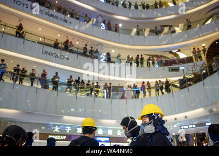 Hongkong, China. 17 Aug, 2019. Die maskierten Teilnehmer der Protestaktion stehen unter den Augen der Passanten in der Moko Einkaufszentrum im Stadtteil Kowloon. In Hongkong gab es massive Proteste für mehr als zwei Monate. Die Demonstrationen wurden durch eine Gesetzesvorlage der Regierung ausgelöst - jetzt in der Warteschleife - Verdacht auf Auslieferung von Verbrechern zu China. Credit: Gregor Fischer/dpa/Alamy leben Nachrichten Stockfoto