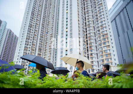 Hongkong, China. 17 Aug, 2019. Die Teilnehmer an einem Protestmarsch durch die Hongkongs Stadtteil Kowloon vor einem Hochhaus, und selbst mit Sonnenschirmen vor dem Regen schützen. In Hongkong gab es massive Proteste für mehr als zwei Monate. Die Demonstrationen wurden durch eine Gesetzesvorlage der Regierung ausgelöst - jetzt in der Warteschleife - Verdacht auf Auslieferung von Verbrechern zu China. Credit: Gregor Fischer/dpa/Alamy leben Nachrichten Stockfoto