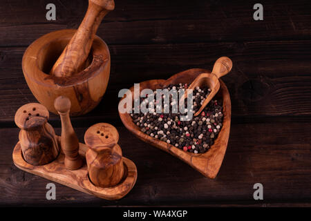 Holz- Mörtel mit kleinen hölzernen Löffel für Gewürze, Pfeffer, Low Key, Olivenholz, rustikal. Stockfoto