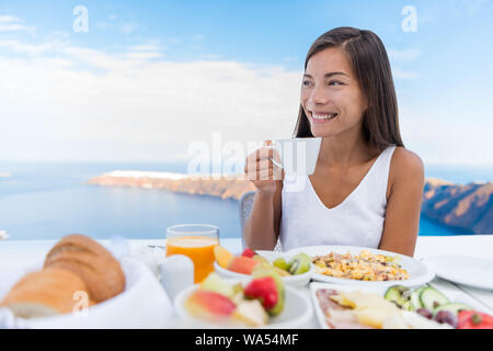 Asiatische Frau trinkt Kaffee am Morgen Frühstück. Schöne elegante Dame mit Kaffeetasse auf Luxus hotel Terrasse mit Meerblick im Resort Restaurant in Oia Santorini, Griechenland. Stockfoto
