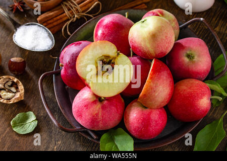 Apple backen saisonale Konzept. Zutaten für Apfelkuchen close-up (roter Apfel, Mehl, Eier, Anis, Zucker, Haselnuss und Zimt) auf einem rustikalen Holzmöbeln tab Stockfoto