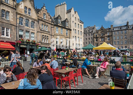 Touristen und Einheimische gleichermaßen draußen essen und genießen einige Frühsommer Sonne in Grassmarket, Edinburgh, Schottland, Großbritannien. Stockfoto