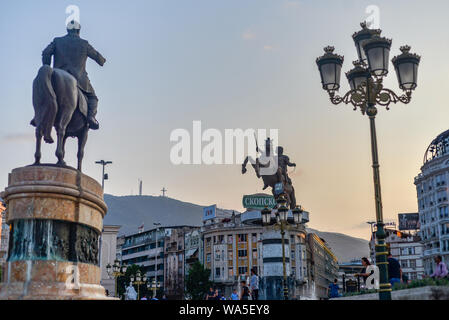 Die Statuen und bulldings und Brunnen der Mittelpunkt von Skopje, die mit Millennium Kreuz auf der Oberseite des fernen Berg Vodno. Stockfoto