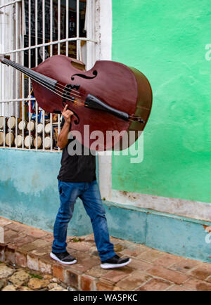 Trinidad, Kuba, 26. November 2017 - Der Mensch geht hinunter die Straße mit seinem Cello auf seiner Schulter Stockfoto