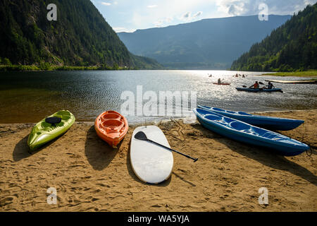 Szene Sommer drei Valley Lake mit Kajaks, Kanus, und andere Freizeit watercrafts liegen auf dem sandigen Strand, während einige Leute sind Kajak, können Stockfoto