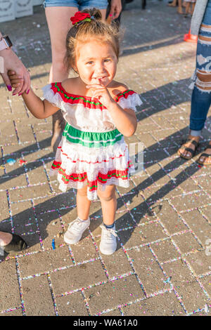 Ein wenig Hispanic Mädchen in einem besonderen Buntes Kleid die Hand ihrer Mutter im Fiesta Mercado del Norte in Santa Barbara, Kalifornien Holding gekleidet. Stockfoto