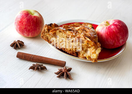 Ein Stück Apfel Kuchen mit Zimt und frische Äpfel auf dem hölzernen Tisch Stockfoto