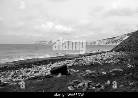 Ein Paddel-boarder und Schwimmer im Meer in Compton Chine Beach Compton Bay auf der Isle of Wight Stockfoto