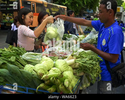 BANGKOK, THAILAND - Juni, 21, 2017: Ein Mann verkauft Gemüse an, die ein Kunde von seiner Karre auf einer Straße Stockfoto