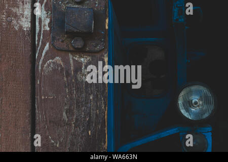 Abstrakte Komposition der Hälfte der ländlichen braun Scheune Tor und ein Teil der sehr alten blauen Traktor. Traktor und Türen sind in die Fokussierung der Kamera Stockfoto