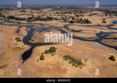 Antenne des Okavango Delta Wasserlauf durch trockenes Land - Atemberaubende bunte Landschaft in der trockenen Jahreszeit Stockfoto