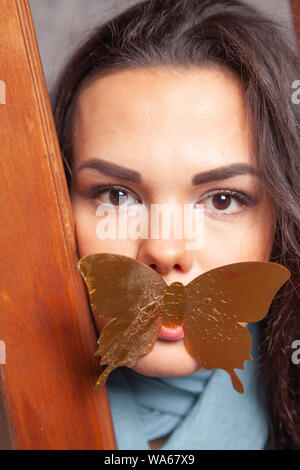 Junge mixrace Frau spielt mit goldenen Papier Schmetterling Stockfoto