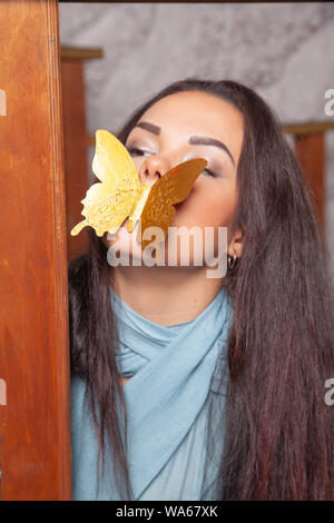 Junge mixrace Frau spielt mit goldenen Papier Schmetterling Stockfoto