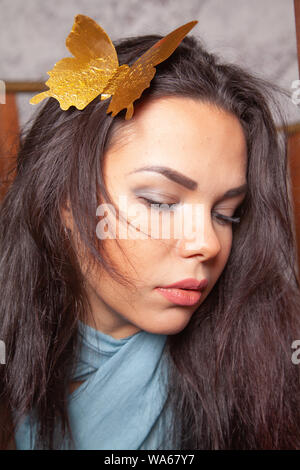 Junge mixrace Frau spielt mit goldenen Papier Schmetterling Stockfoto