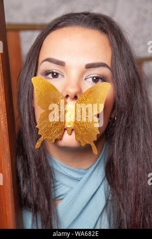 Junge mixrace Frau spielt mit goldenen Papier Schmetterling Stockfoto