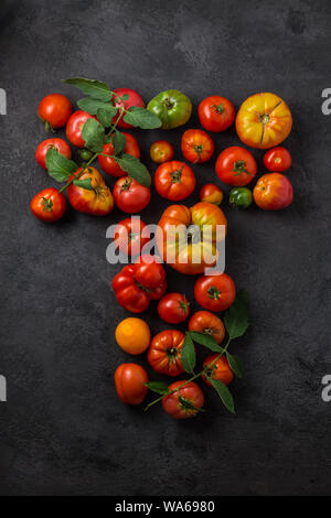 Buchstabe T mit reifen Tomaten auf einem schwarzen Hintergrund, kreative Flach gesundes Essen Konzept. Stockfoto