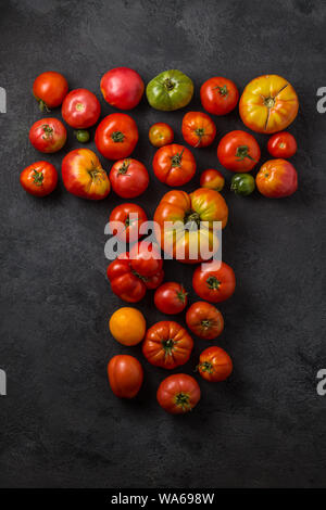 Buchstabe T mit reifen Tomaten auf einem schwarzen Hintergrund, kreative Flach gesundes Essen Konzept. Stockfoto