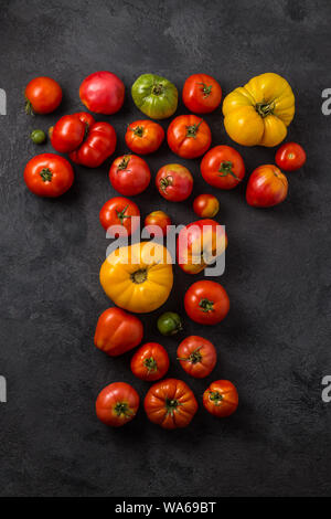 Buchstabe T mit reifen Tomaten auf einem schwarzen Hintergrund, kreative Flach gesundes Essen Konzept. Stockfoto