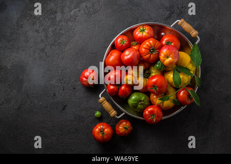 Reife Tomaten in einer Pfanne auf schwarzem Stein, kopieren. Stockfoto