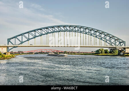 Zwolle, Niederlande, 24. Juli 2019: Blick entlang dem Fluss IJssel mit den alten blauen IJssel Brücke im Vordergrund und die neuen roten Hanzeboog railwa Stockfoto