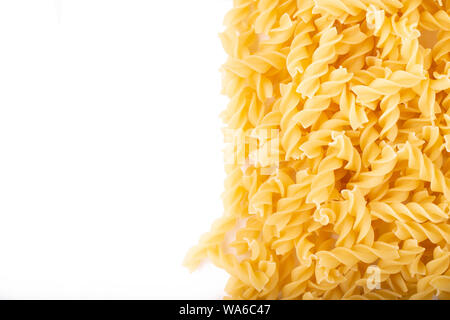 Raw spiralförmige Pasta auf weißem Hintergrund verstreut. Traditionelle italienische Speisen. Platz für Text Stockfoto